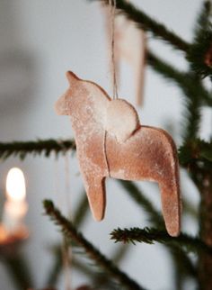 an ornament shaped like a cat hanging from a christmas tree with candles in the background