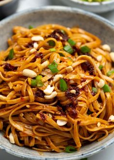 a bowl filled with noodles and nuts on top of a table