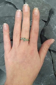 a woman's hand with a ring on it and some rocks in the background