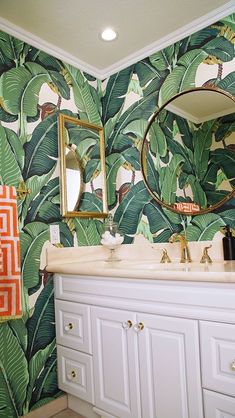 a bathroom decorated with tropical wallpaper and mirrors