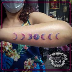 a woman wearing a face mask and holding up her arm with the word moon tattooed on it