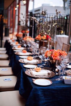 a long table is set with place settings and flowers