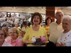 an older woman is holding a cake with candles on it as others look on in the background