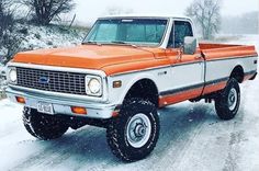 an orange and white truck parked in the snow