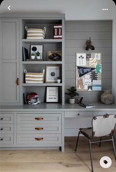 an office with gray painted cabinets and white chairs in front of the desk is filled with books