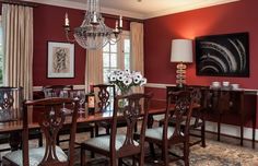 an elegant dining room with red walls and chandelier