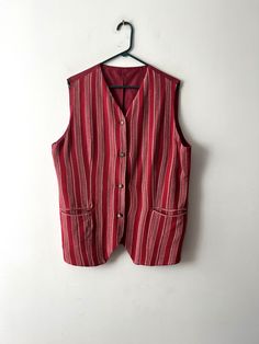 "Vintage 90s summer vest Red striped vest Hippie Festival long vest Sleeveless long shirt Button Down Fitted Comfortable vest Size XL Estimated size: XL Measurements (lying flat): Length: 27.5\"/ 70 cm Pit to pit: 22.5\"/ 57.3 cm Waist: 22\"/ 56 cm Please check measurements to insure a proper fit. Remember to allow yourself some extra room for movement. You can compare these with something from your closet that fits you well. This vest will come to you freshly laundered and ready to wear. Please convo me if you need additional measurements. Condition: great Vintage Condition SHIPPING * I ship worldwide via Priority mail (Latvijas Pasts) from Latvia (EU). * I ship from Europe, so please allow 2 to 4 weeks for the package to arrive if you live overseas. * Europe 5 - 10 business days. Thanks Striped Cotton Sweater Vest For Summer, Red Vest With Pockets, Red Sleeveless Vest With Pockets, Summer Striped Cotton Vest, Vintage Red Vest For Summer, Red Vintage Vest For Summer, Red Vintage Summer Vest, Sleeveless Vest With Vertical Stripes For Spring, Red Sleeveless Vest With Buttons