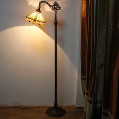 a lamp that is on top of a floor next to a window with curtains behind it