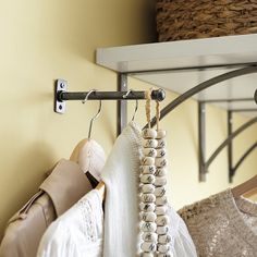 some clothes hanging on a rack next to a basket and coat hanger in a room