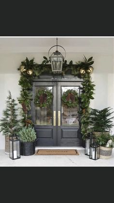 the front door is decorated for christmas with wreaths and potted plants on either side