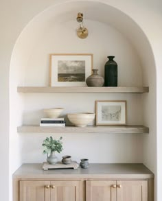 some shelves with vases and pictures on them in a room that has white walls