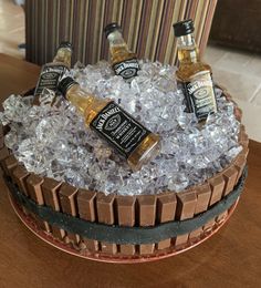 three bottles of whiskey sitting on top of ice in a barrel shaped container with brown and black trim