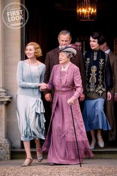 an older woman in a pink dress is walking with two younger women and one man