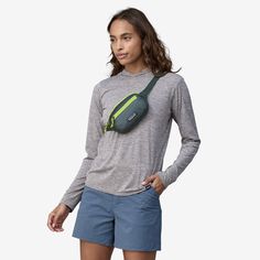 a woman in grey shirt and blue shorts with green fanny bag on her back pocket