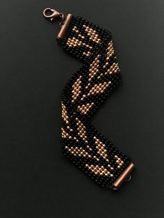 a pair of black and gold beaded bracelets on a black surface with a hook