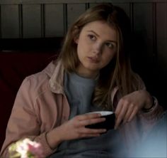 a woman sitting on a couch holding a remote control