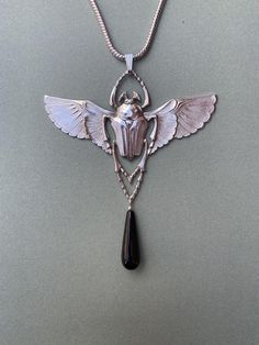 A highly detailed Egyptian Revival design dating from the 1920's featuring a winged scarab. Scarabs symbolised eternity in Egyptian mythologyThe pendant and chain are 5 micron silver plate on brass, nickel free and hypoallergenic. The 18 inch chain is included with the pendant. The measurements are 9cm wide x 7cm tall.I have also used a semi precious black Onyx drop to finish off the piece.Free worldwide shipping is included Medieval Vampire, Winged Scarab, Revival Design, Celtic Viking, Wedding Women, Clear Quartz Point, Egyptian Revival, Women Necklace, Vintage Pendant