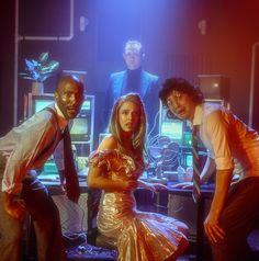 three people standing in front of a computer screen