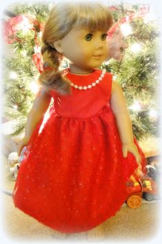 the doll is wearing a red dress and pearls