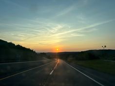 the sun is setting on an empty highway