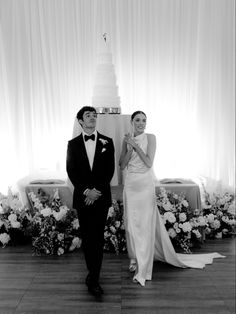 a man and woman standing next to each other in front of a cake