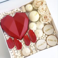 a heart shaped box filled with lots of different types of candies and cookies next to flowers