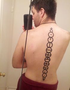 a man taking a selfie with his cell phone in front of him and tattoos on his back