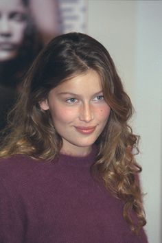 a young woman with long hair wearing a purple sweater and posing for the camera in front of a movie poster