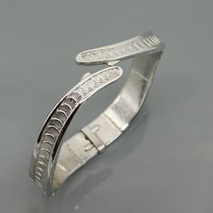 Vintage Monet bangle bracelet is silver tone metal with a bypass design. This hinged bangle has a unique design with a wider bottom and slowly tapering near the top with the bypass. At the base it is about 1/2 inch wide and each side of the bypass is 1/8 inch at the very tip. The bracelet is a sort of rounded square rather than a typical bracelet that is round. The highlight is the overlapping shell like design that runs all the way around the bangle. Bracelet is about 6 1/2 inches wearable leng Nickel-free Silver Bangle Cuff Bracelet, Silver Hinged Bangle As Gift, Silver Hinged Bangle For Wedding, Adjustable Silver Bangle With Oyster Bracelet, Hinged Sterling Silver Bangle In Silver, Silver Hinged Bracelets For Weddings, Silver Hinged Bracelet For Wedding, Silver Hinged Bracelet As A Gift, Formal Silver Hinged Bangle