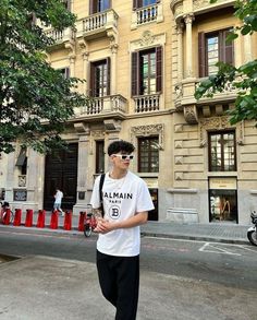 a young man is standing in front of a building