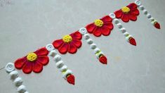 a red and yellow flower design on a white table cloth with beads around the edges