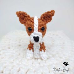 a small dog is sitting in a crocheted basket with a white and brown blanket