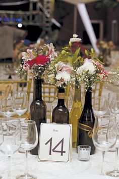 the table is set up with wine bottles and flowers in vases on each side