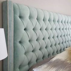 a bed with a light blue headboard and white pillows