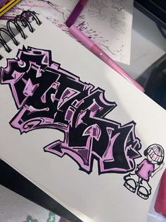 graffiti writing on a piece of paper next to some markers and pencils in the background