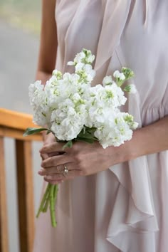 a woman holding a bouquet of white flowers