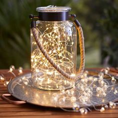 a glass jar filled with lights sitting on top of a wooden table next to a plate