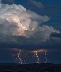 lightning strikes in the sky above a mountain range at night with clouds and dark blue skies