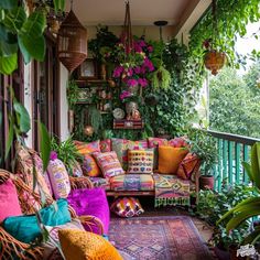 an outdoor porch with lots of plants and colorful pillows on the couch, along with hanging potted plants