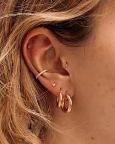 a close up of a woman's ear with two gold hoops on it