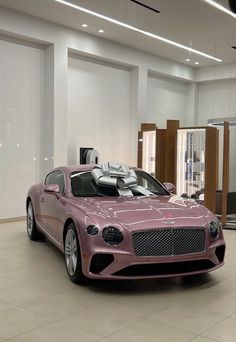 a pink car is parked in a showroom