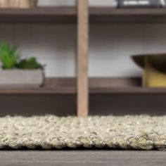 a white rug on the floor in front of a book shelf with books and plants