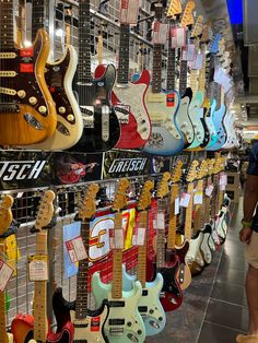 a man standing in front of a display of guitar heads and neck styles for sale