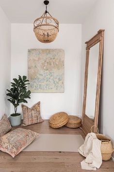 a room with a large mirror and some pillows on the floor next to a potted plant