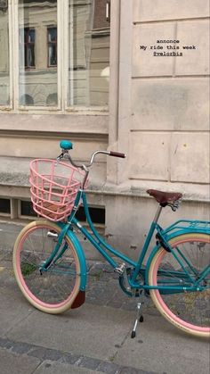 a blue and pink bike parked on the side of a street next to a building