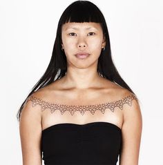 a woman wearing a strapless top with an intricate design on her arm and shoulder