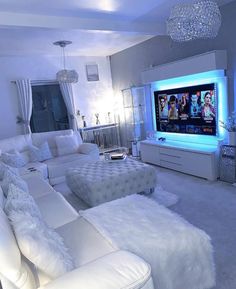 a living room filled with white furniture and a flat screen tv mounted to the wall