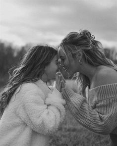 two young women are kissing in the grass