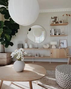 a white vase with flowers sitting on top of a table in front of a mirror