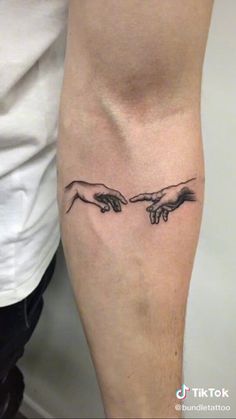 two hands touching each other with the creation behind them tattoo on the left calf leg